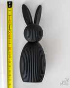 Black bunny figure next to measuring tape for scale