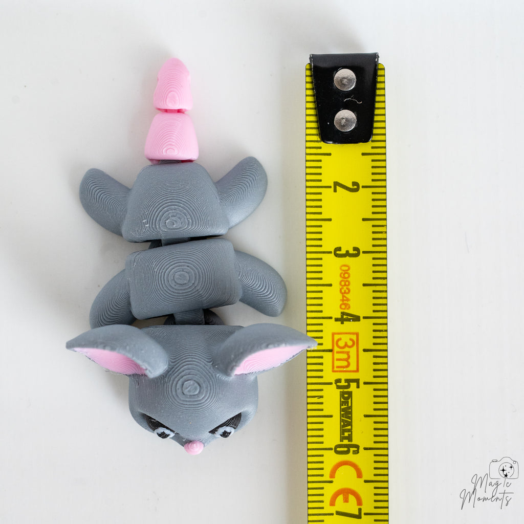 Grey mouse figurine with pink nose and ears next to a yellow measuring tape for scale