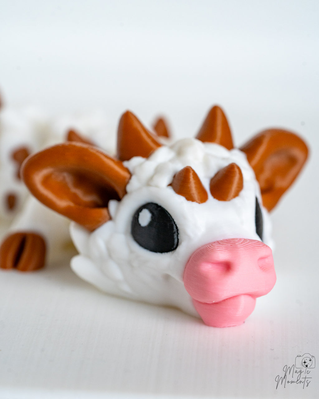 Close-up of a cow dragon with brown horns and a pink nose on a white background.