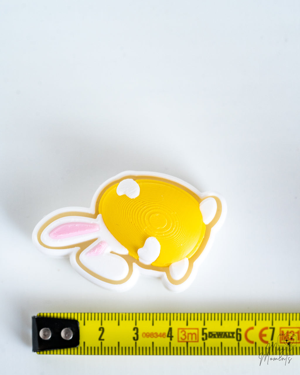 Yellow bunny clicker next to measuring tape for scale