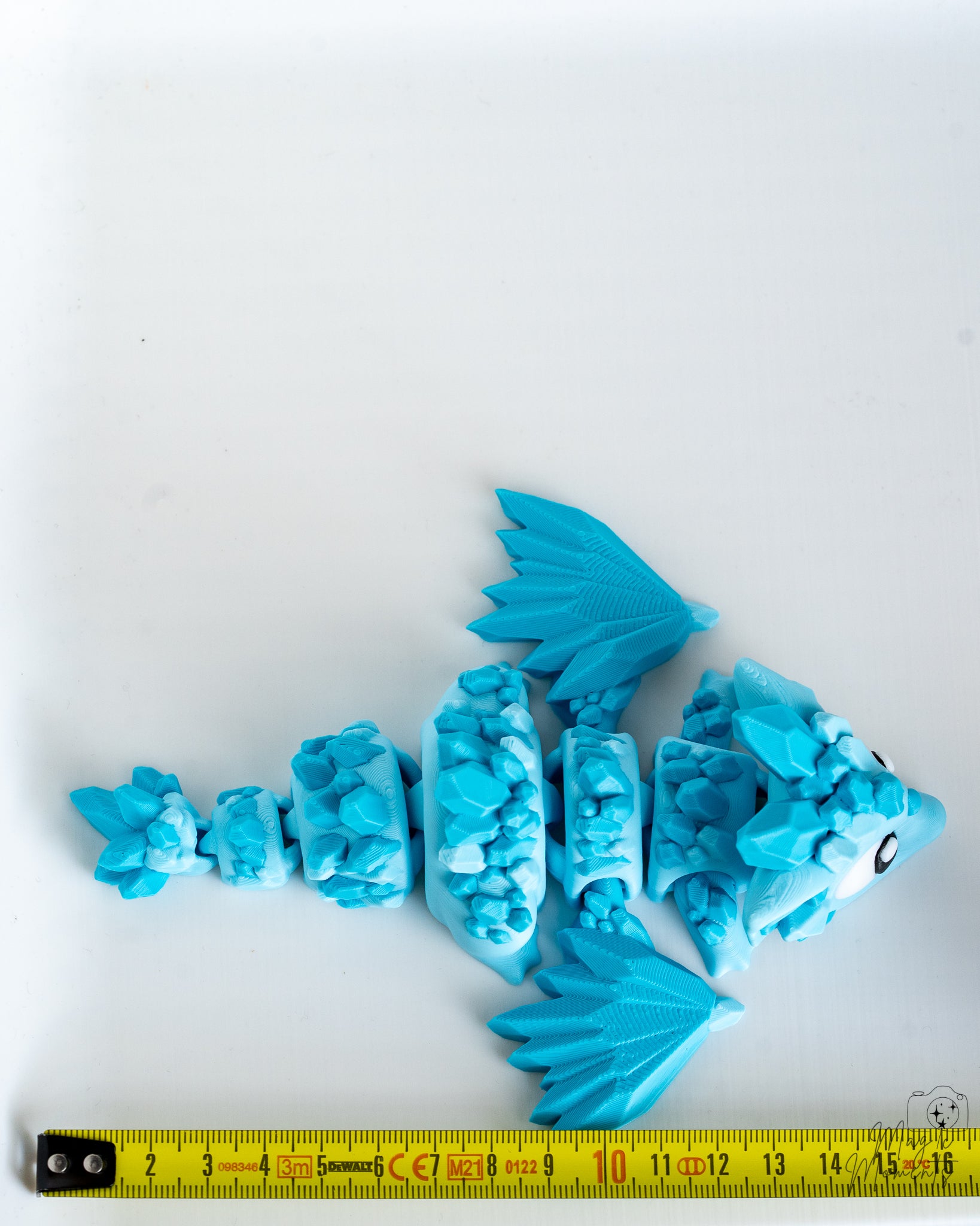 Articulated blue crystal dragon next to measuring tape for scale