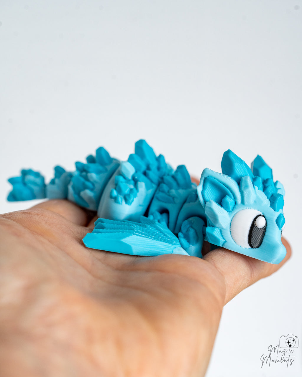 Articulated blue dragon held in hand for scale