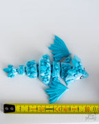 Articulated blue crystal dragon next to measuring tape for scale