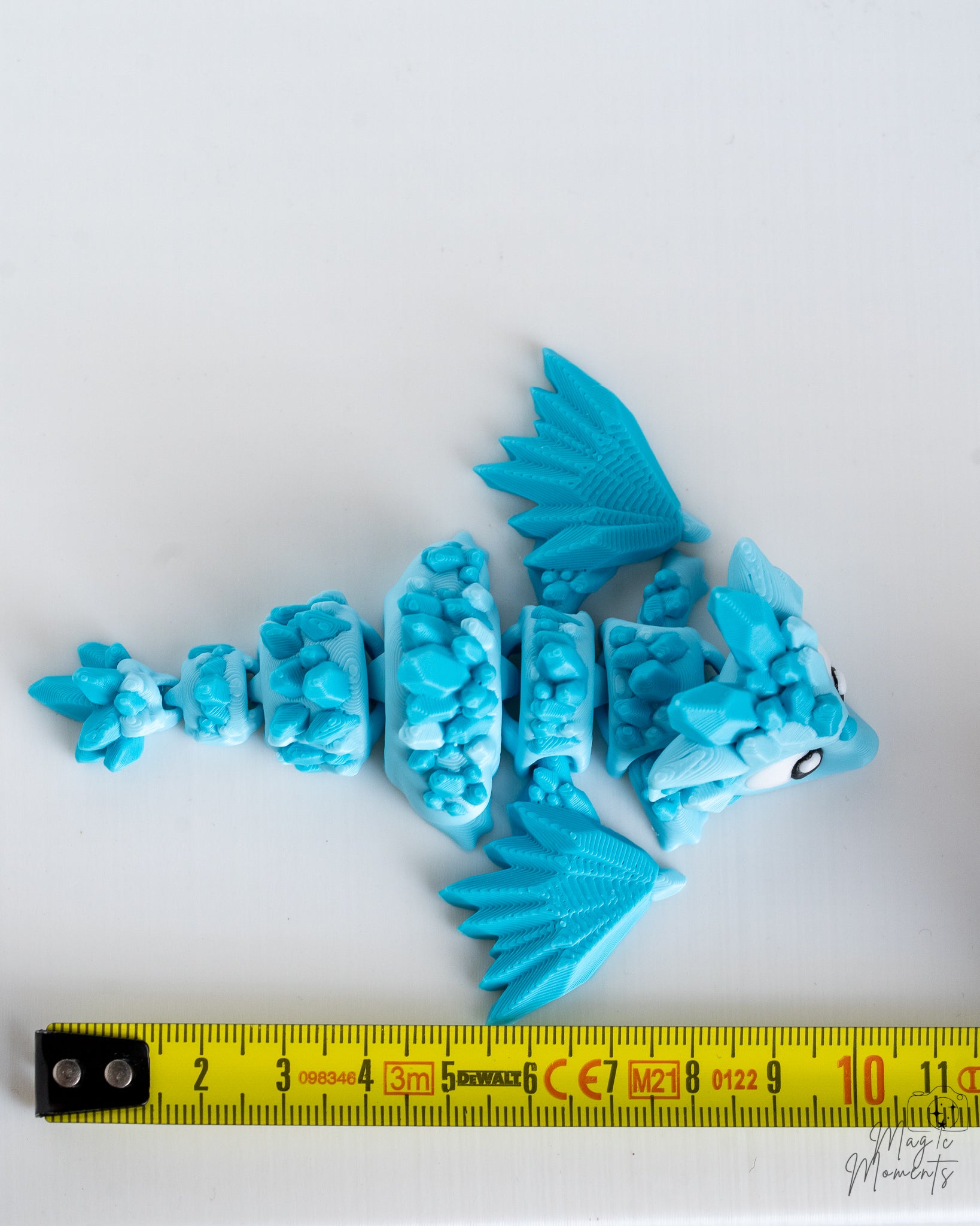 Articulated blue crystal dragon next to measuring tape for scale