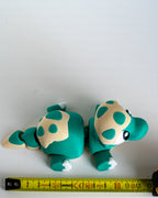 Teal articulated dinosaur next to measuring tape for scale