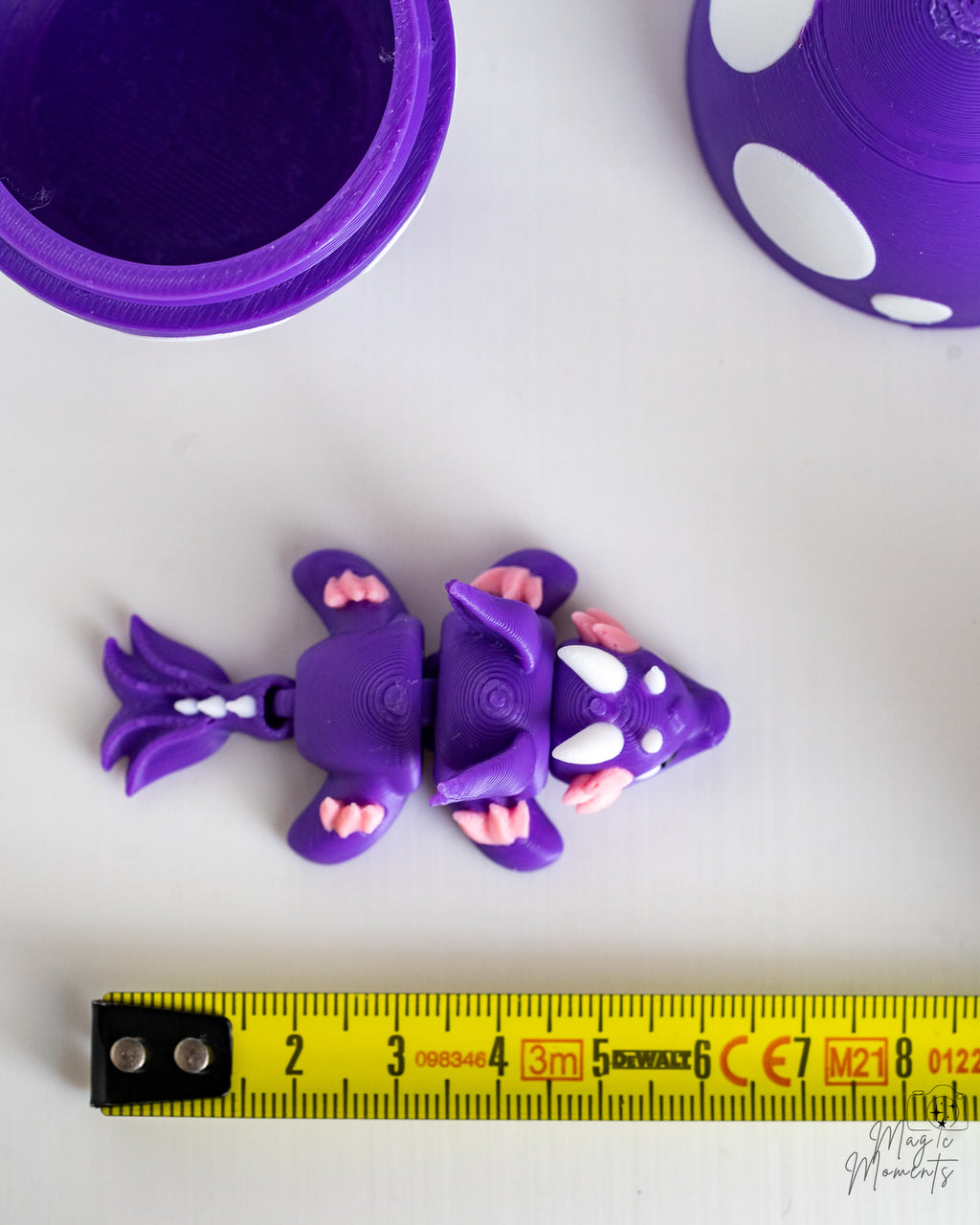Mini purple dragon figure next to measuring tape for scale