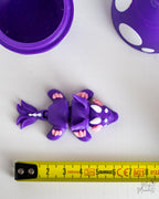 Mini purple dragon figure next to measuring tape for scale