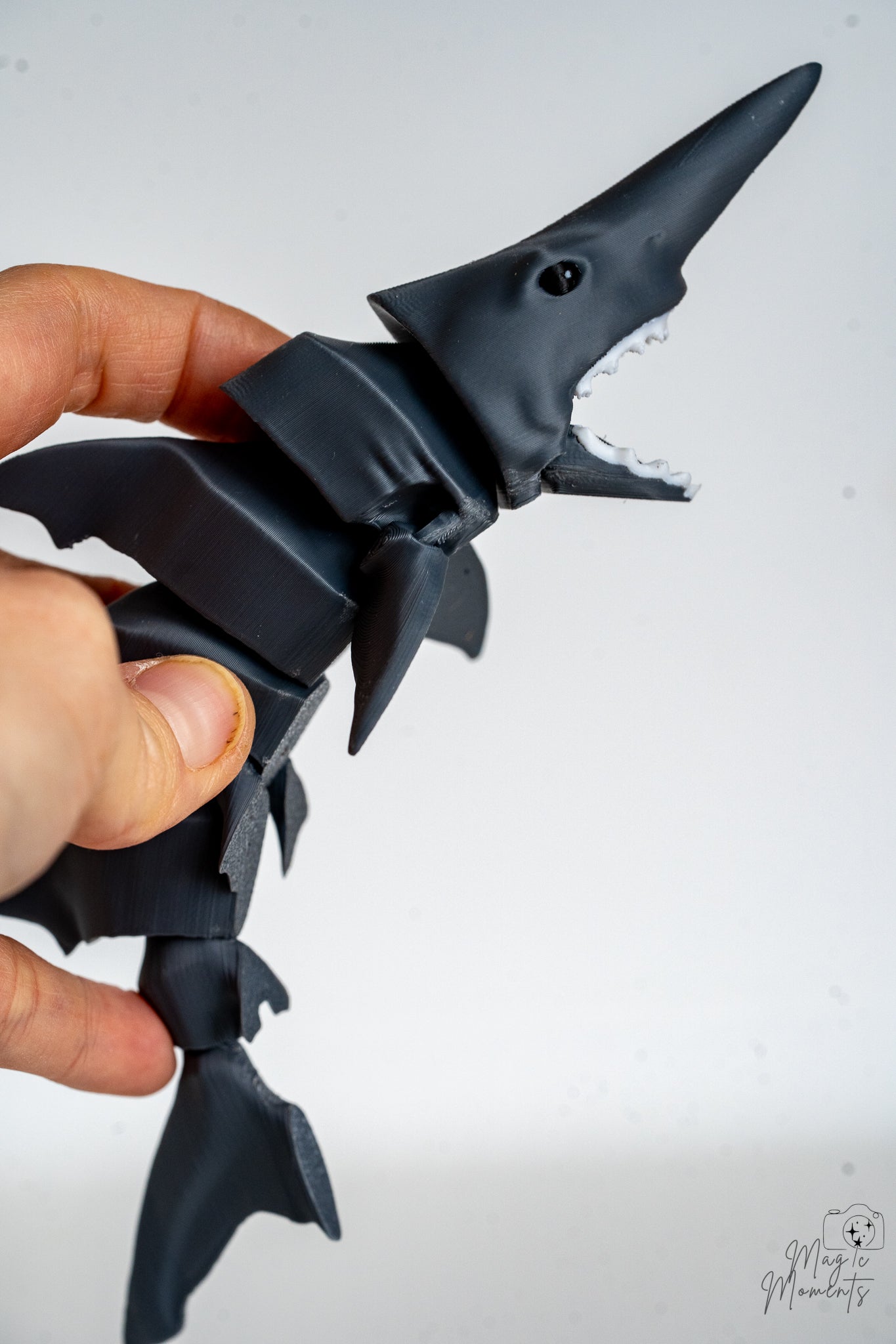 Hand holding articulated shark showing flexible segmented movement