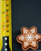 Snowflake gingerbread clicker next to measuring tape for scale