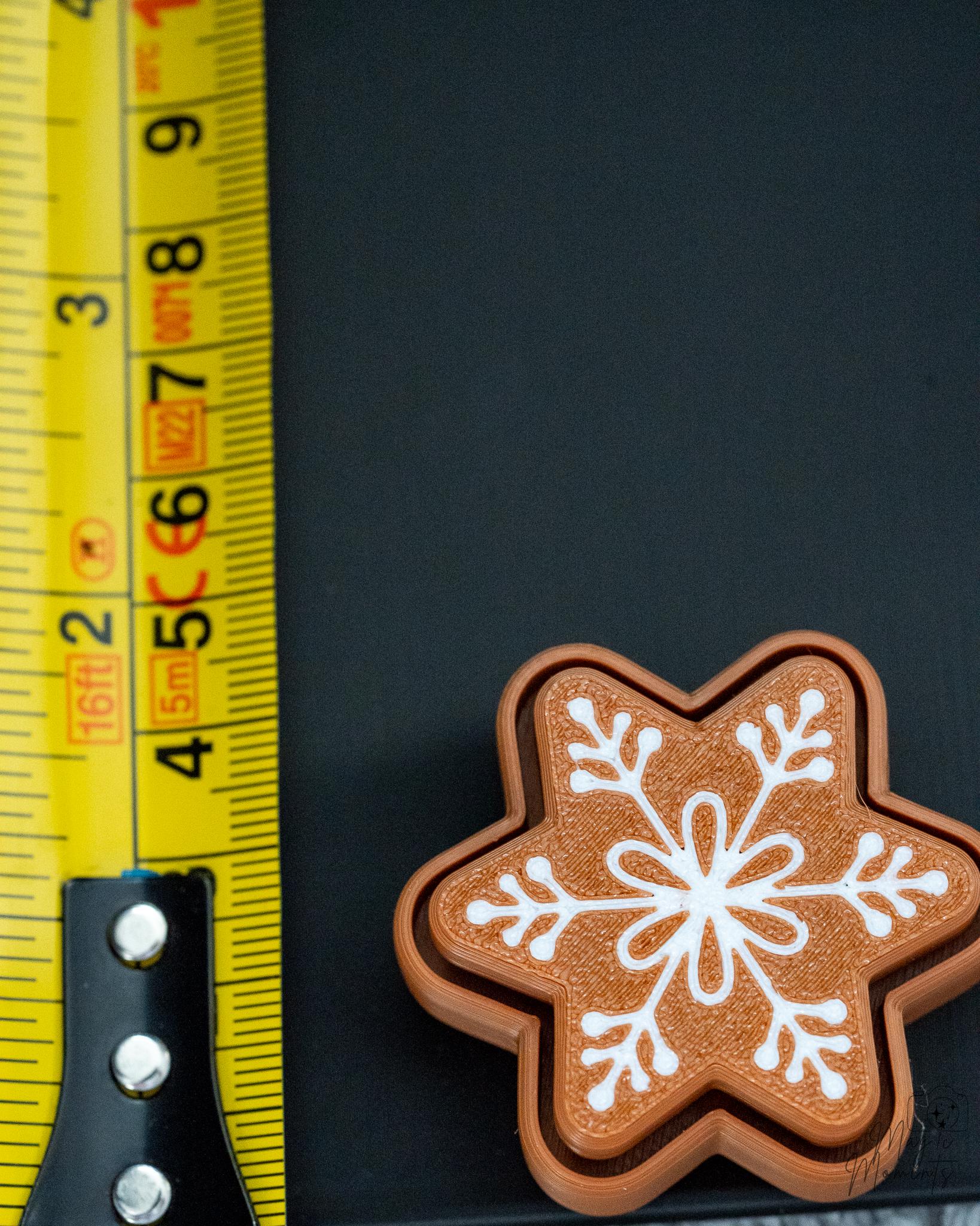 Snowflake gingerbread clicker next to measuring tape for scale