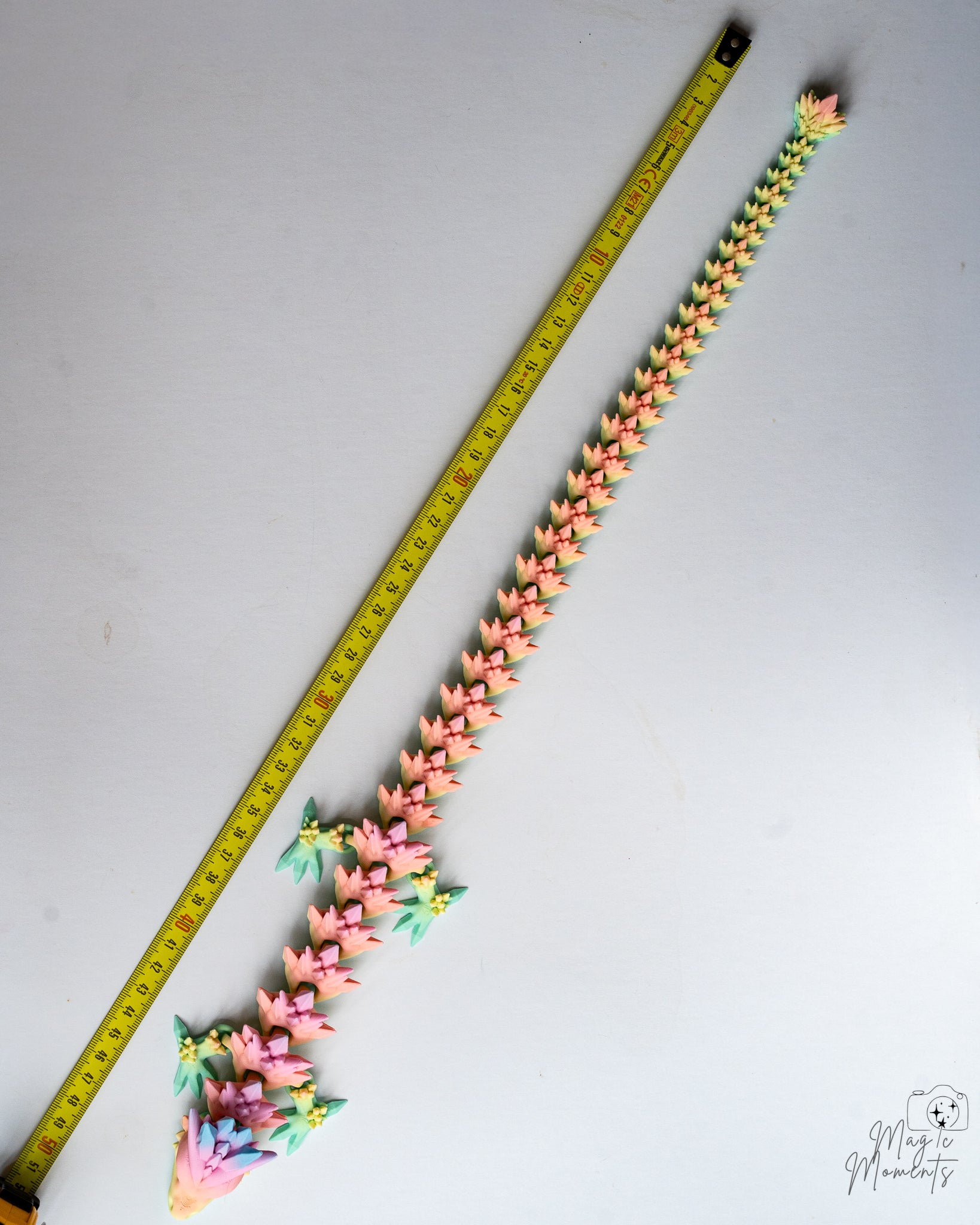 Articulated dragon next to measuring tape for scale