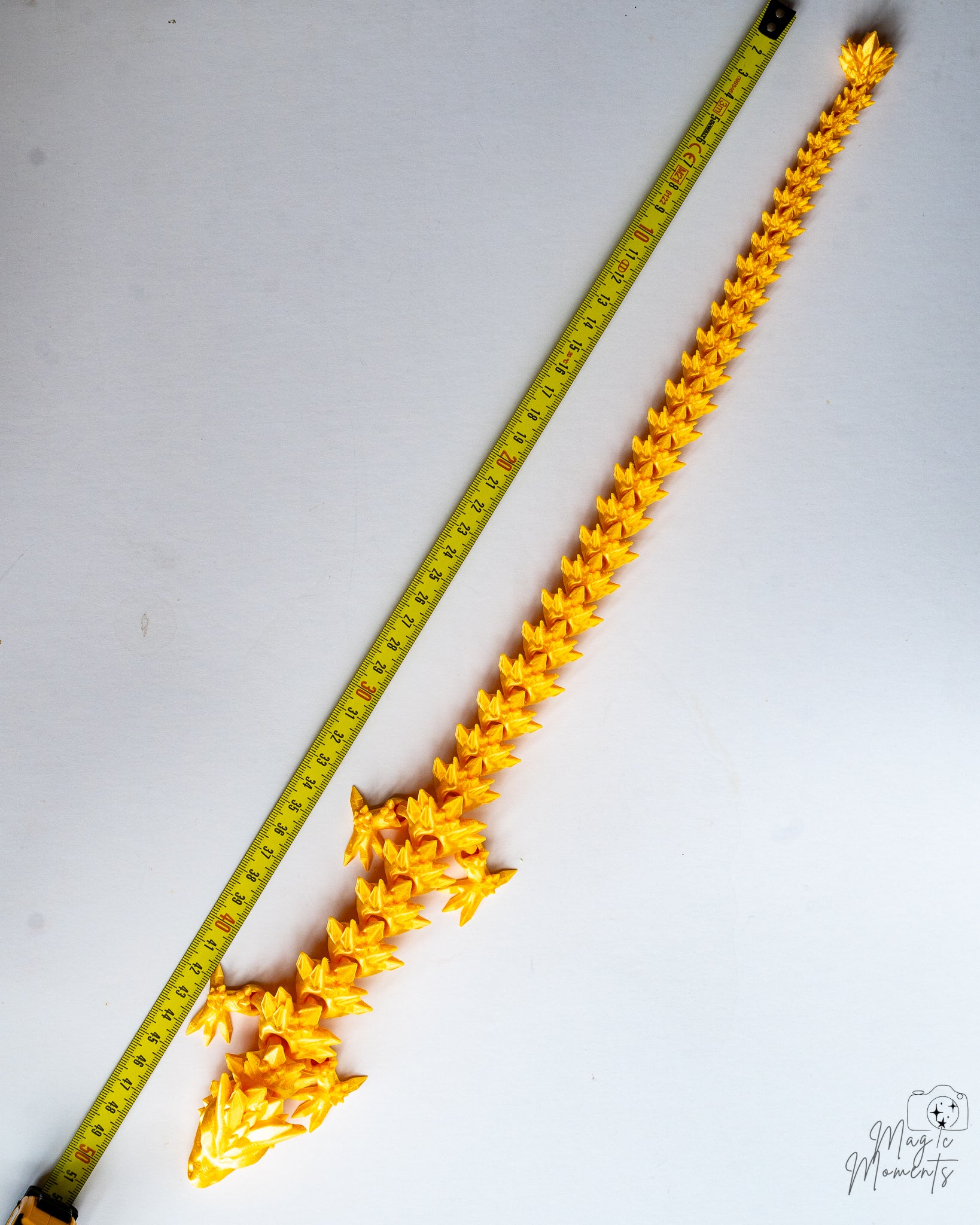 Articulated dragon next to measuring tape for scale