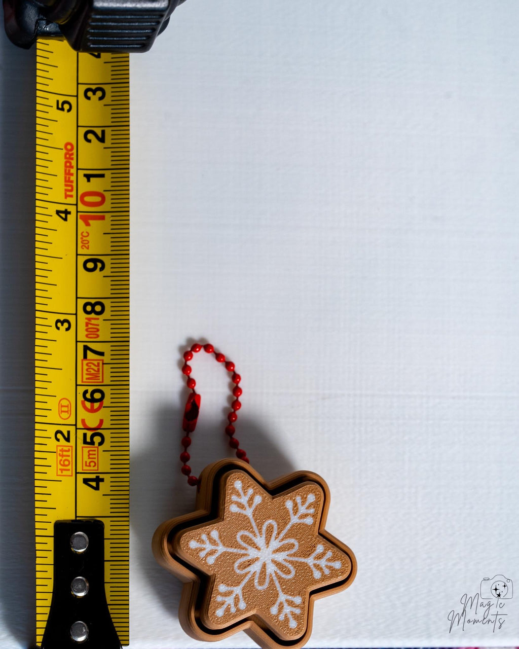 snowflake gingerbread clicker next to measuring tape for scale