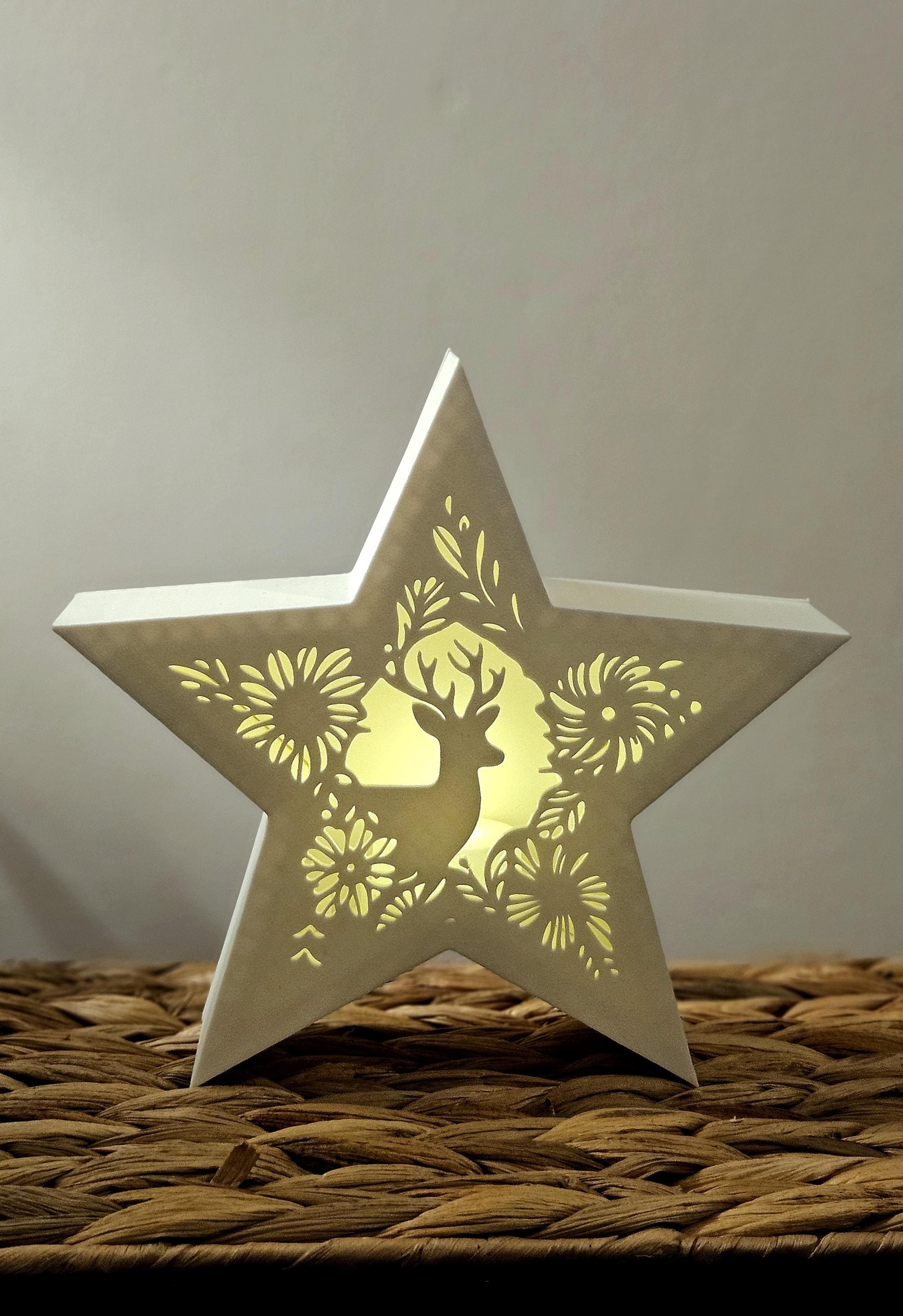 Star-shaped decorative light with a deer design on a woven surface