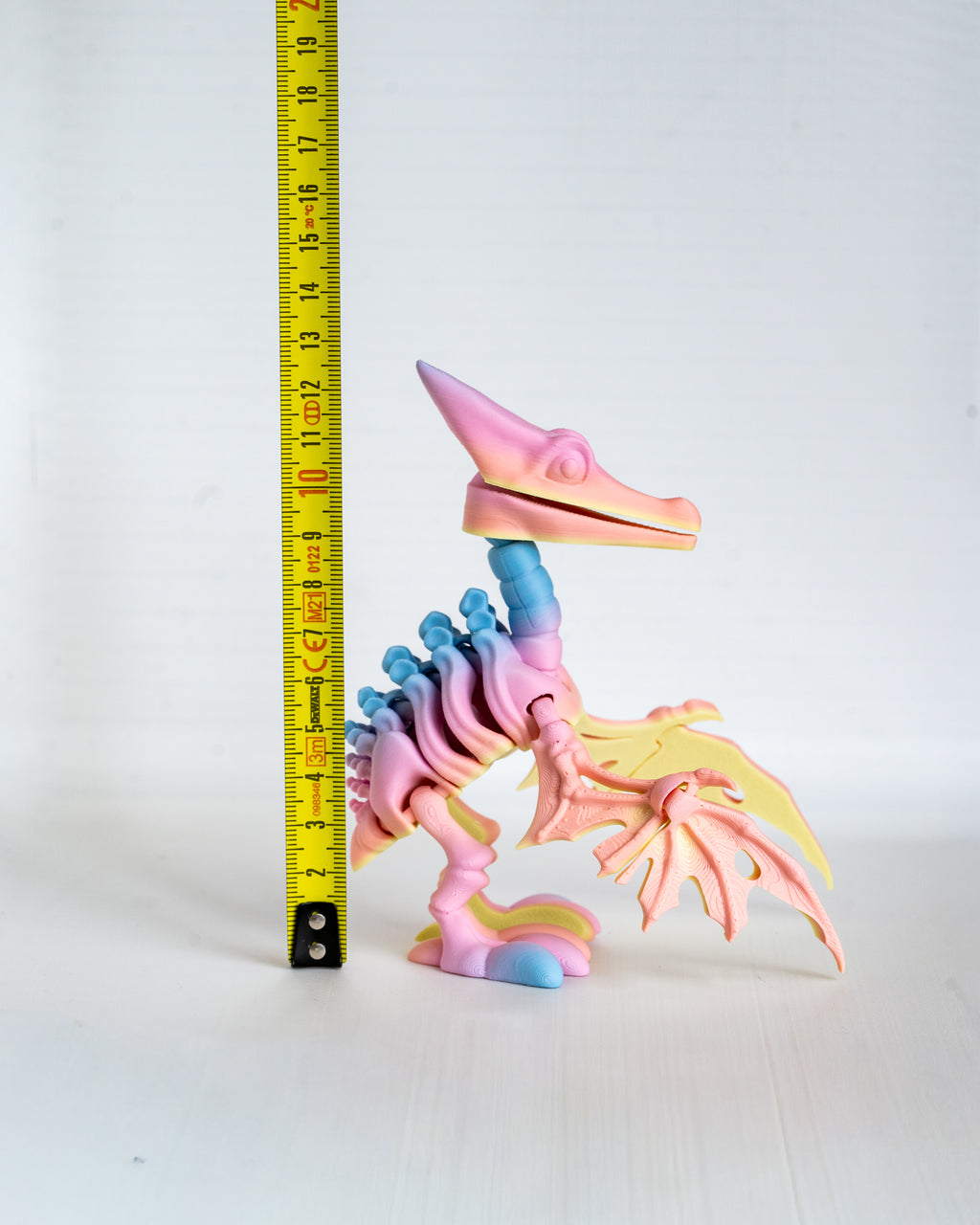 Pink pterodactyl skeleton figure next to measuring tape for scale