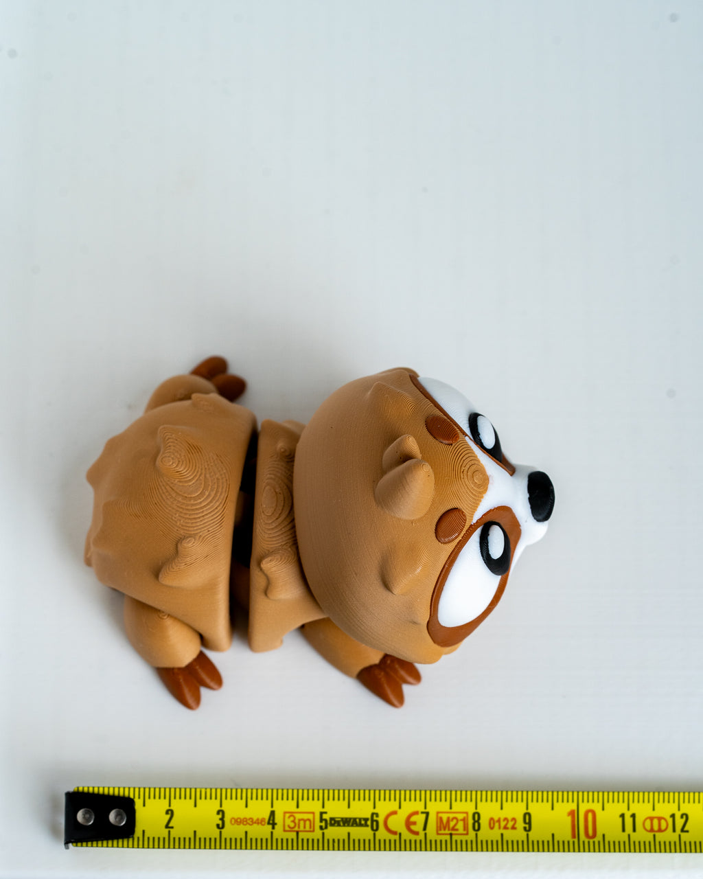 Sloth figure next to measuring tape for scale