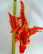 Orange winged dragon next to measuring tape for scale