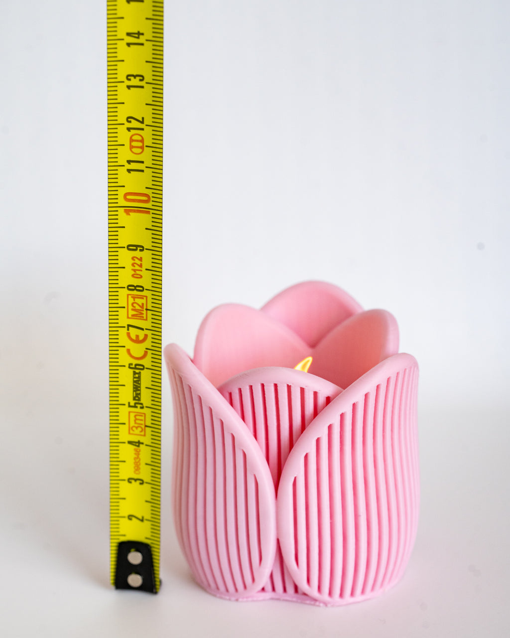Pink tulip tealight holder next to measuring tape for scale