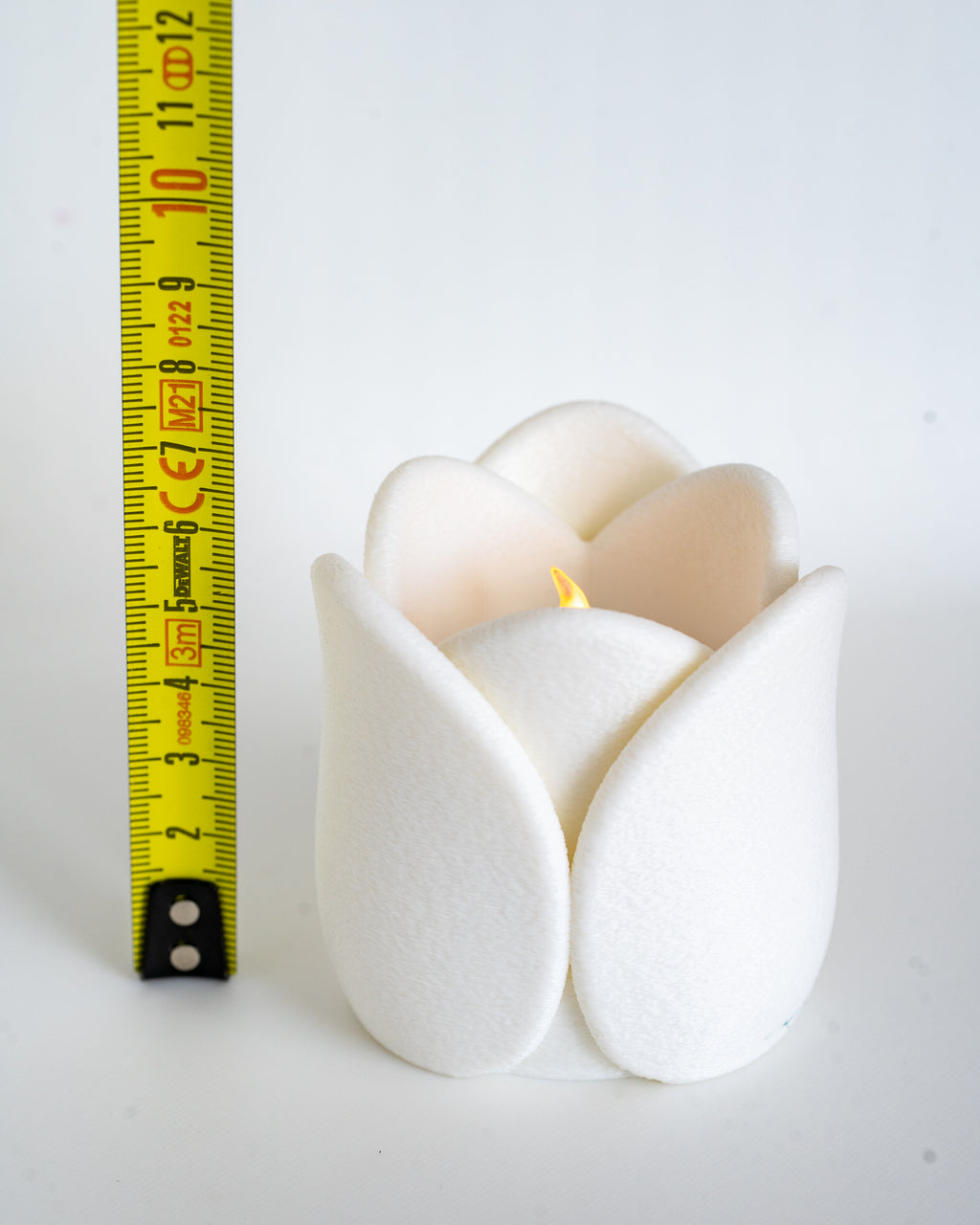 White tulip tealight holder next to measuring tape for scale