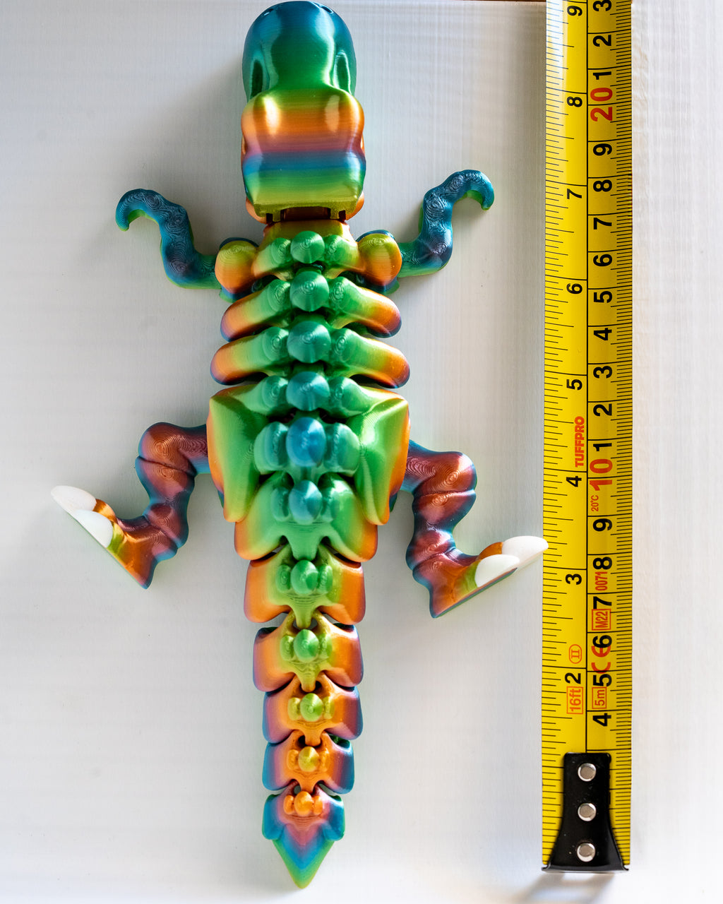 Articulated dinosaur next to measuring tape for scale