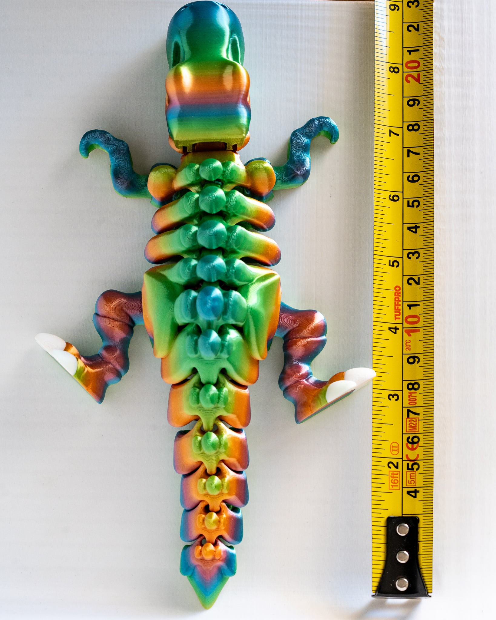 Articulated dinosaur next to measuring tape for scale
