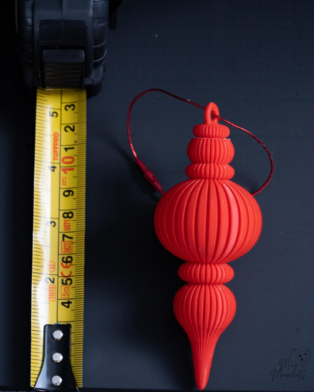 red modern ribbed christmas bauble next to measuring tape for scale