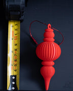 red modern ribbed christmas bauble next to measuring tape for scale