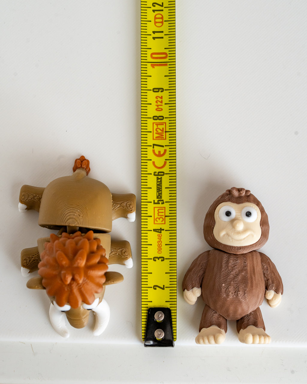 mammoth and Sasquatch figurines next to measuring tape for scale