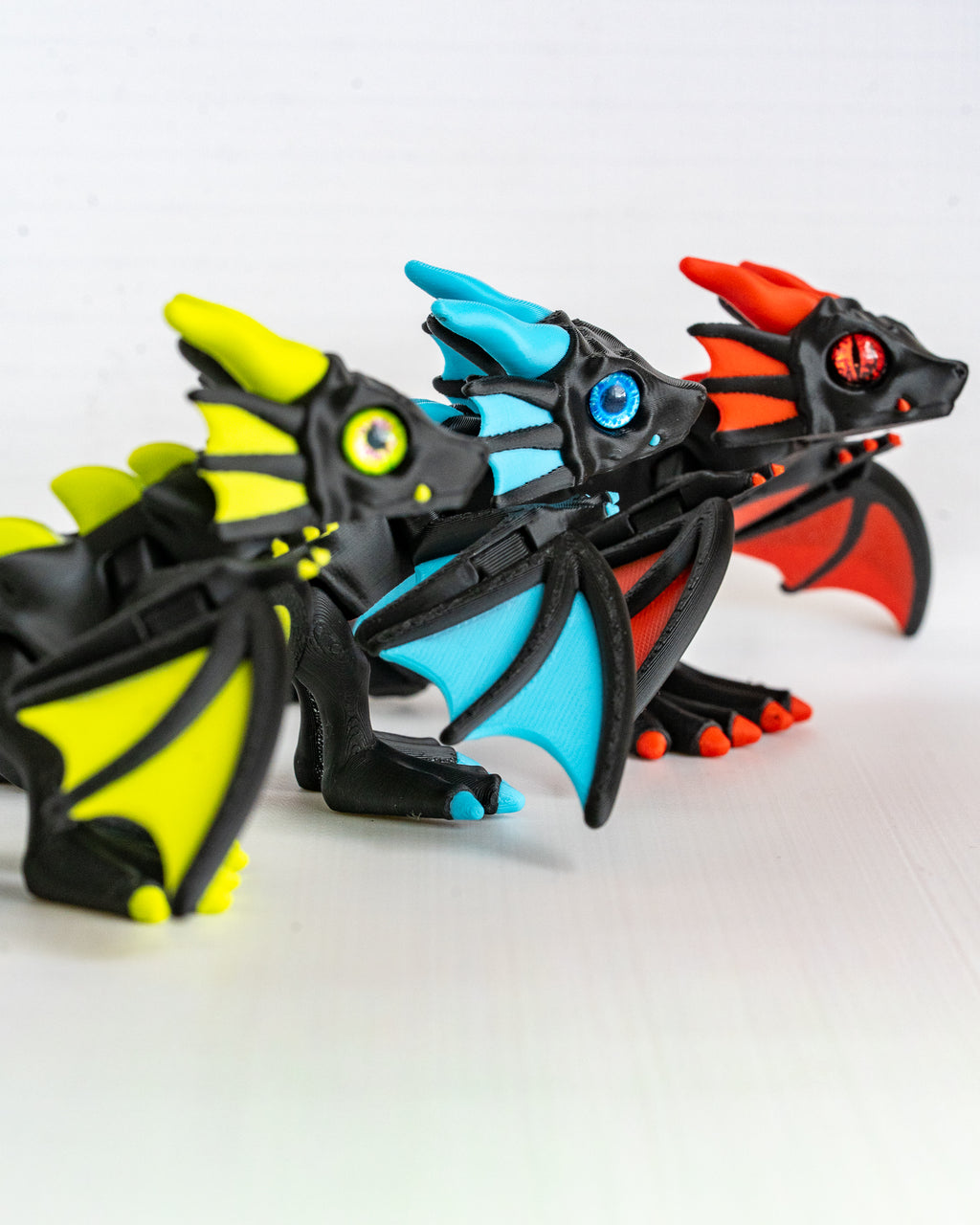 close up Trio of articulated neon dragons in Neon Green Sky Blue and Fire Red