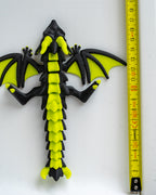Black and green dragon next to a measuring tape on a white background