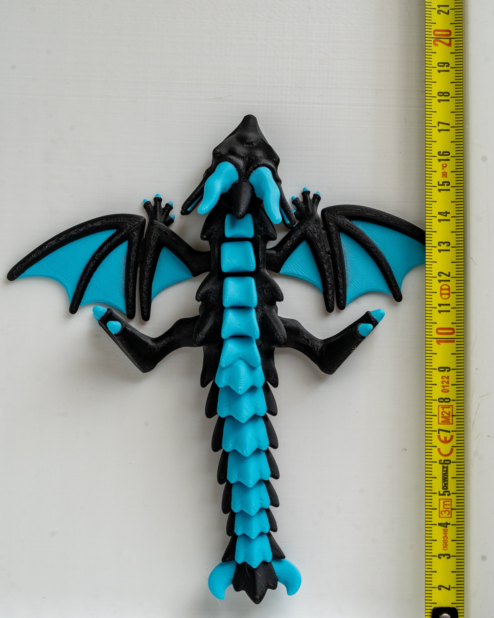 Black and blue dragon with a measuring tape for scale on a white background