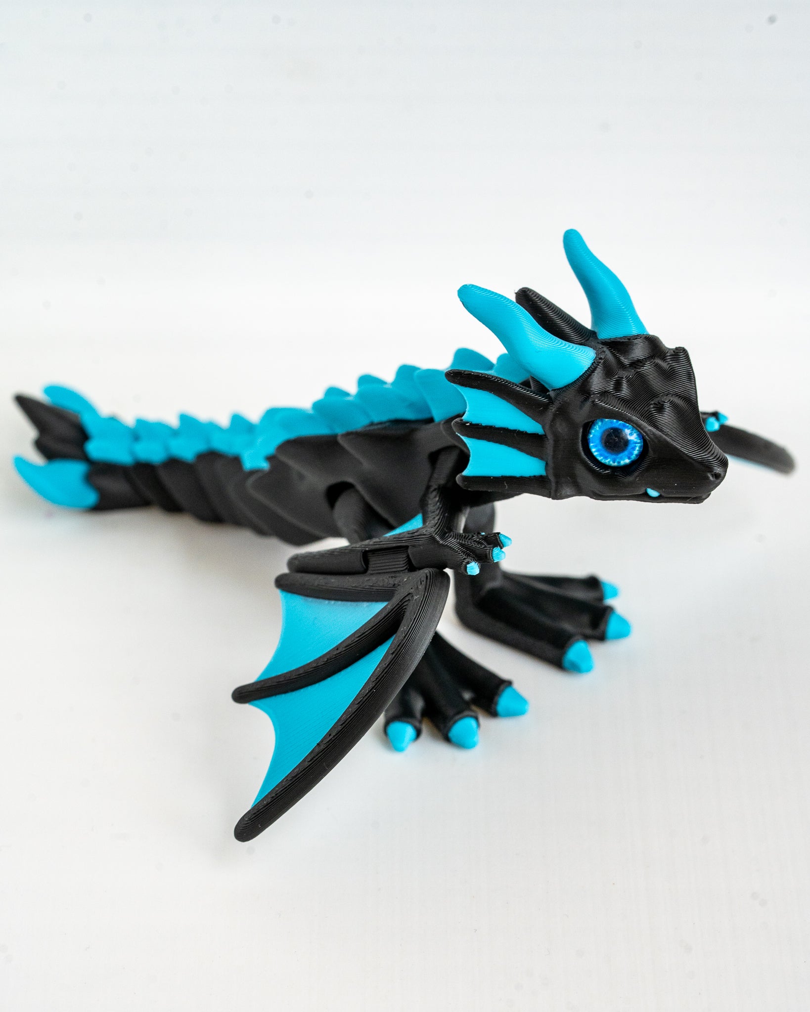 Articulated sky blue and black dragon figurine with detailed wings