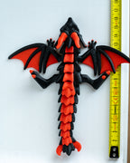 Red and black dragon with a measuring tape  for scale on a white background