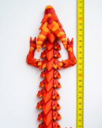 Red and orange dragon figurine next to a ruler on a white background