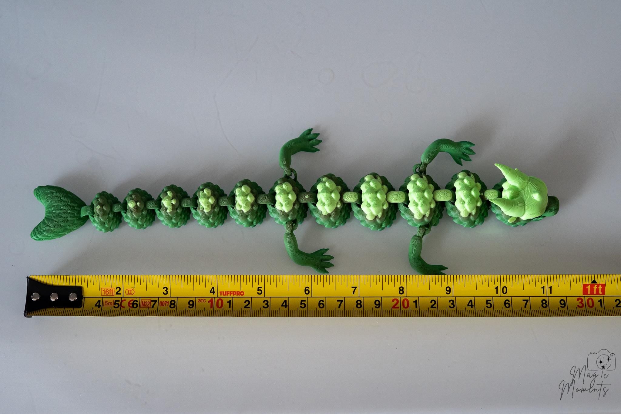 Green dragon next to measuring tape for scale