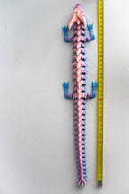 Colorful dragon next to a measuring tape on a white background