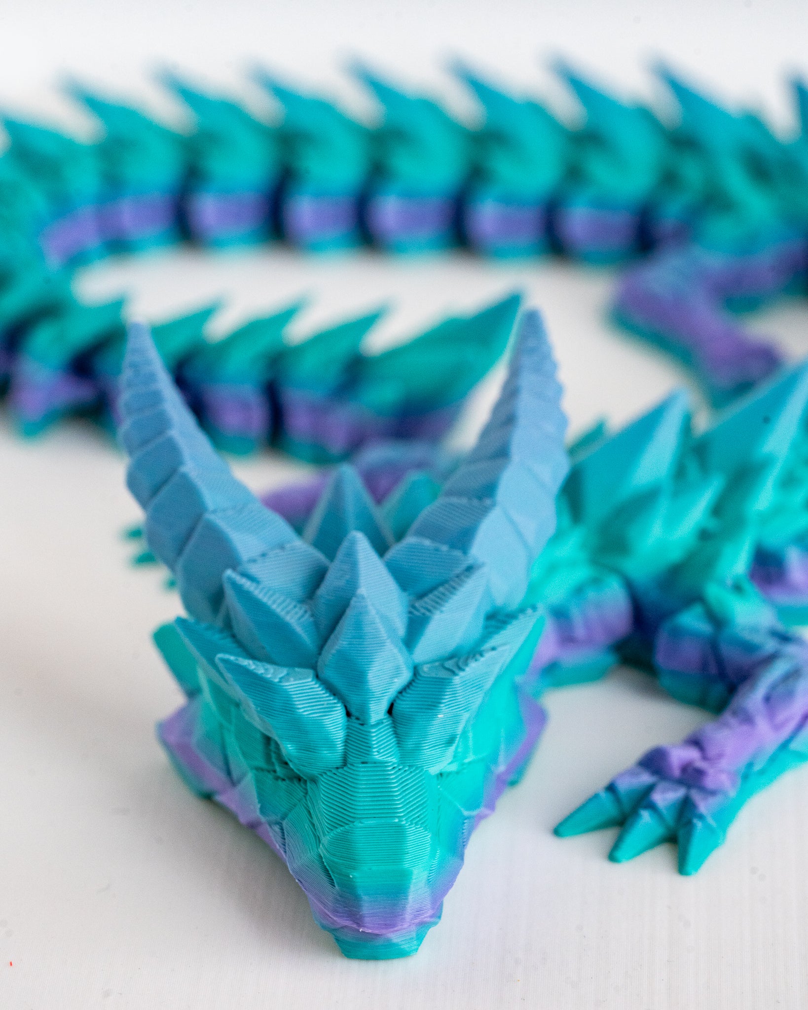 Teal and purple dragon model on a white background