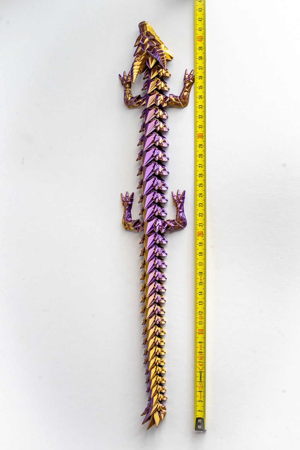 Purple Prismor dragon figure next to measuring tape for scale