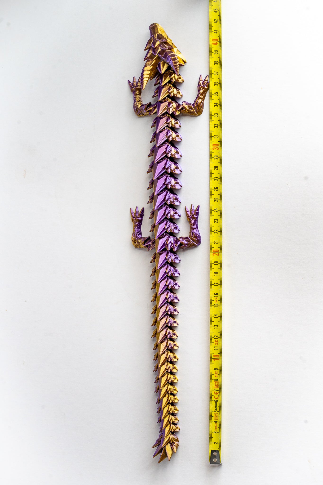 Purple Prismor dragon figure next to measuring tape for scale