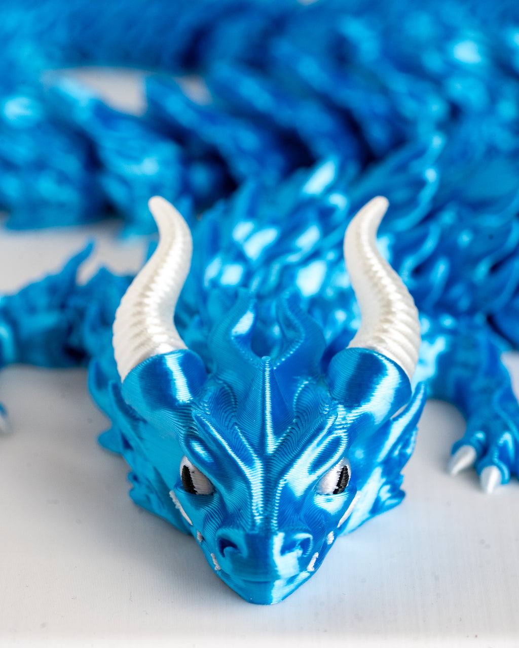 Close-up of a blue dragon figurine with white horns on a light background
