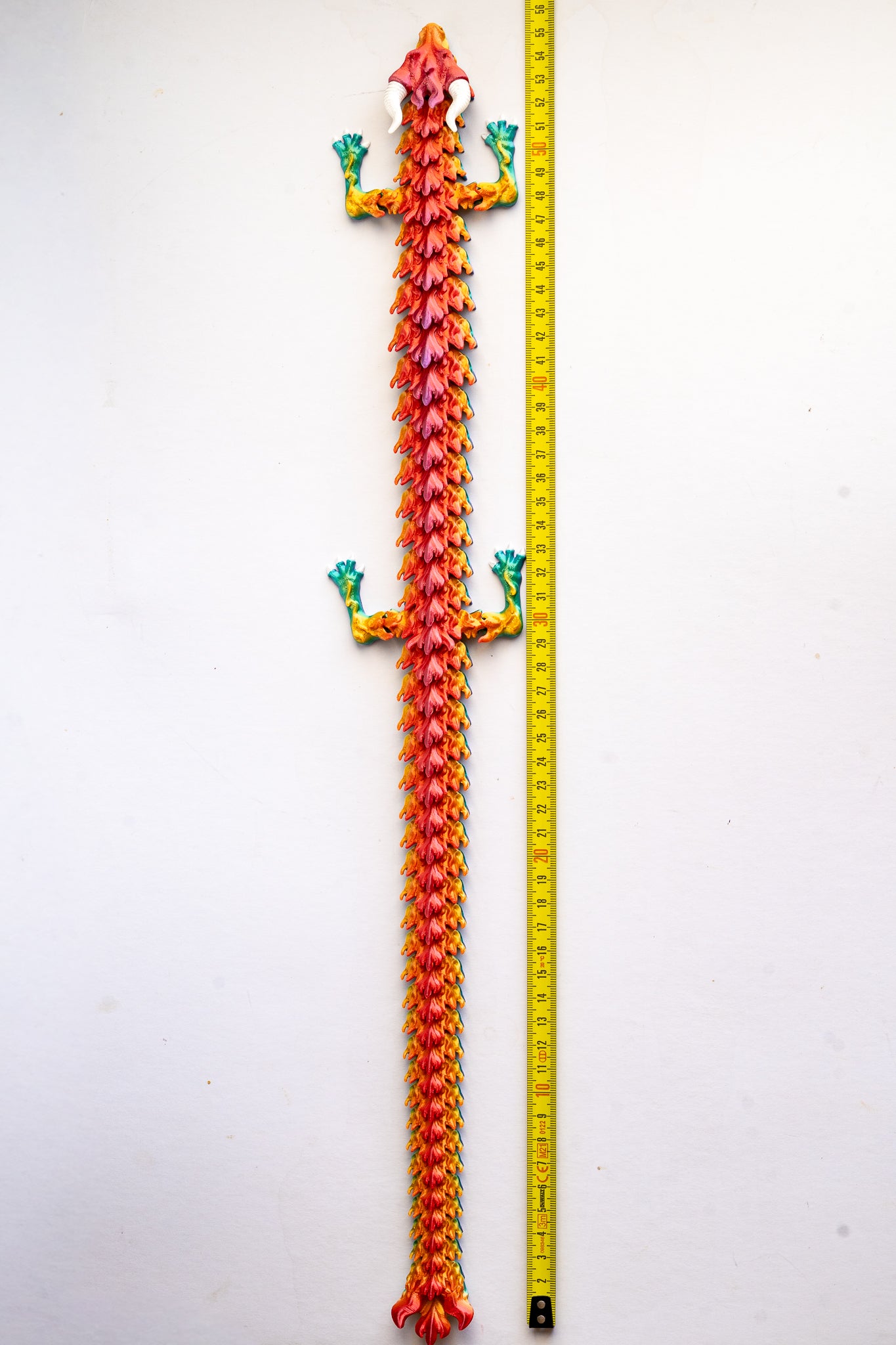 colorful dragon next to a measuring tape for scale on a white background