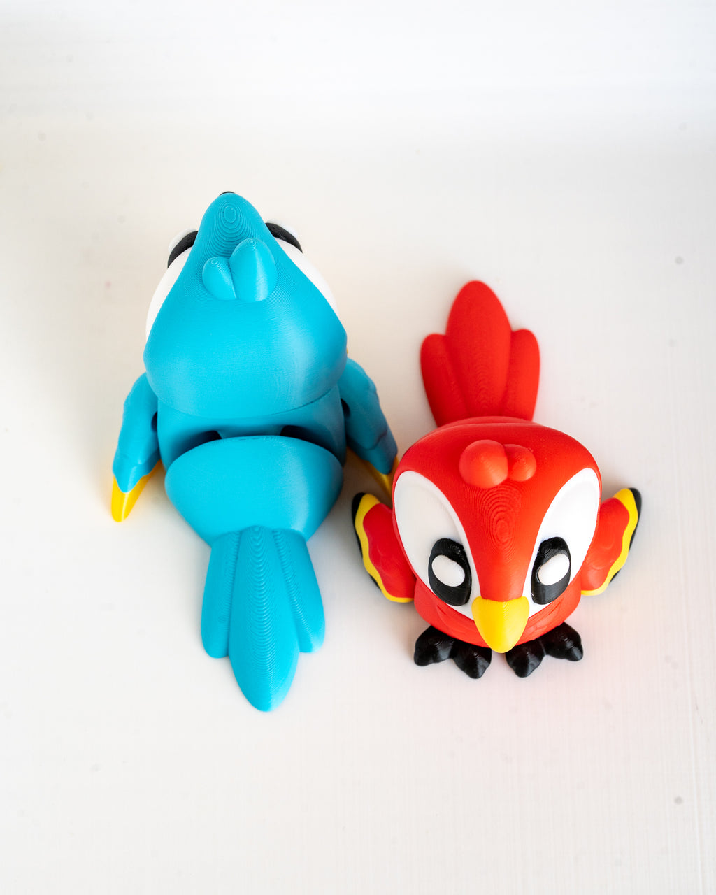 Two colorful cartoon-like figurines, one blue and one red with yellow accents, on a white background.