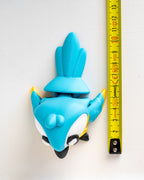 Blue parrot figurine next to a ruler on a white background