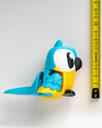 Blue parrot figurine next to a ruler on a white background