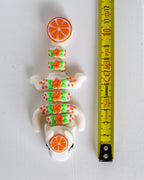 orange dragon figurine next to a yellow measuring tape for scale.