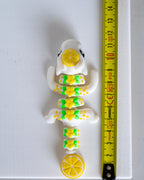 lemon dragon figurine next to a yellow measuring tape for scale.