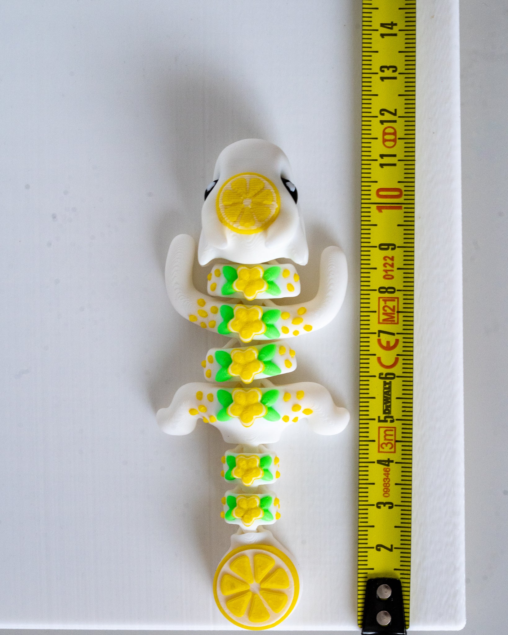 lemon dragon figurine next to a yellow measuring tape for scale.