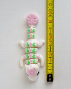 grapefruit dragon figurine next to a yellow measuring tape for scale.