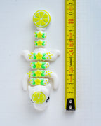 lime dragon figurine next to a yellow measuring tape for scale.