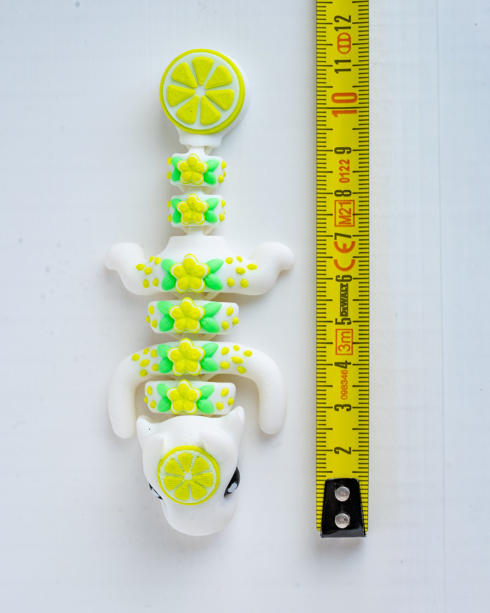 lime dragon figurine next to a yellow measuring tape for scale.